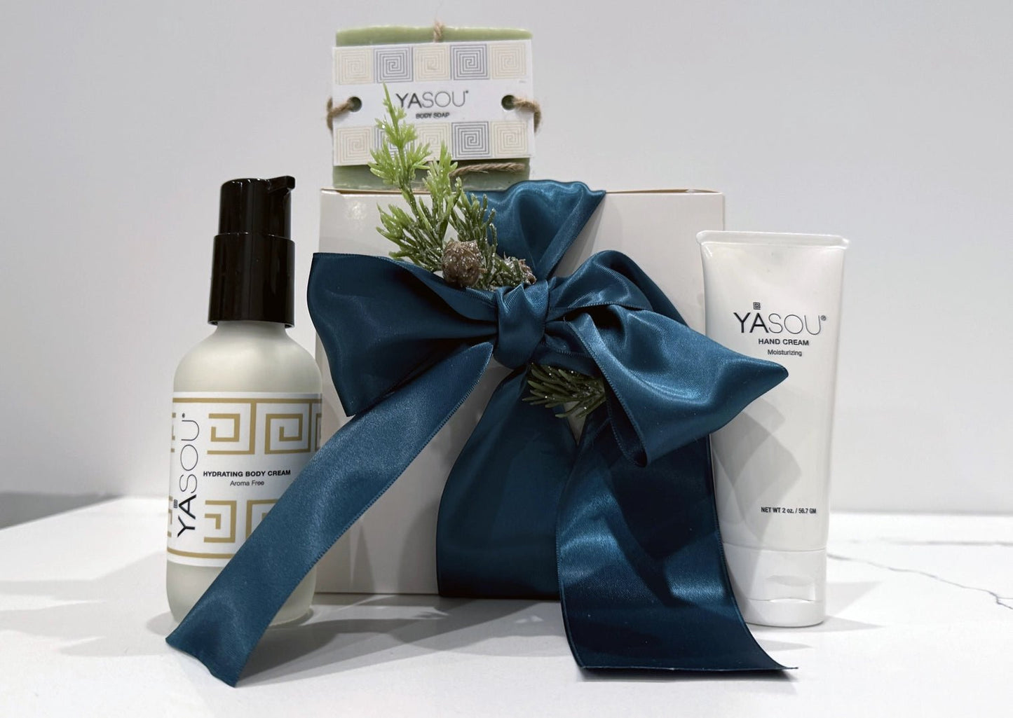 Holiday Gift Box with YASOU skincare products gift wrapped with a teal satin ribbon a white background