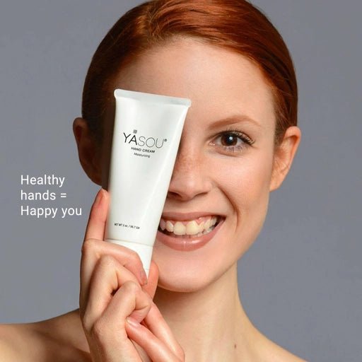 Head shot of young woman holding up over her left eye a tube of YASOU vegan hand cream.