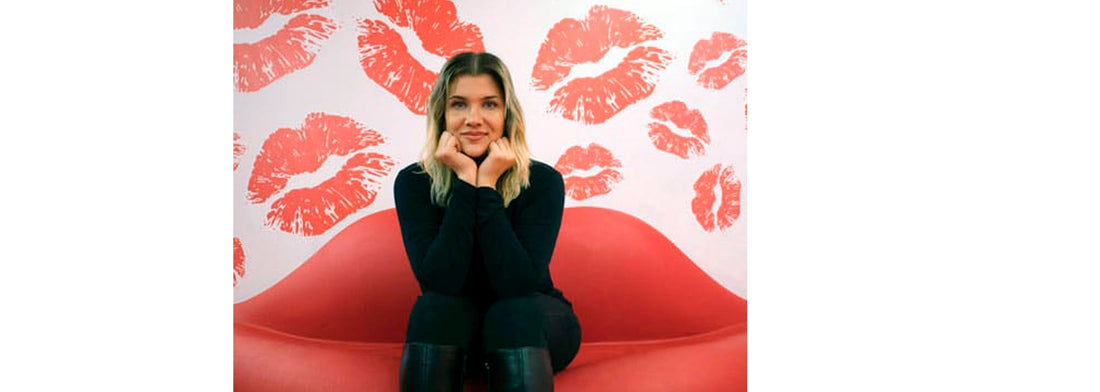 A woman sitting on a couch that looks like lips for YASOU's blog post called "Where to Buy Lip Care Products Online".